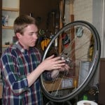Spencer Ingram applies axle grease to the inside of a hub while explaining cup and cone mechanics.