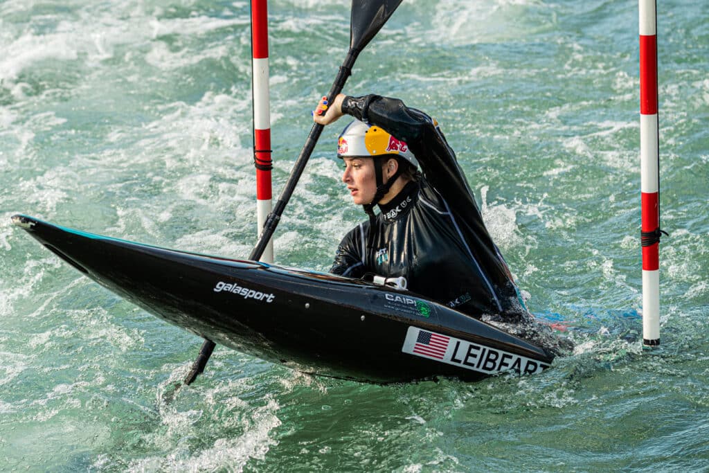 Evy Leibfarth paddles in a slamom kayak on the waters of the US National White Water Center while wearing a RedBull Helmet.