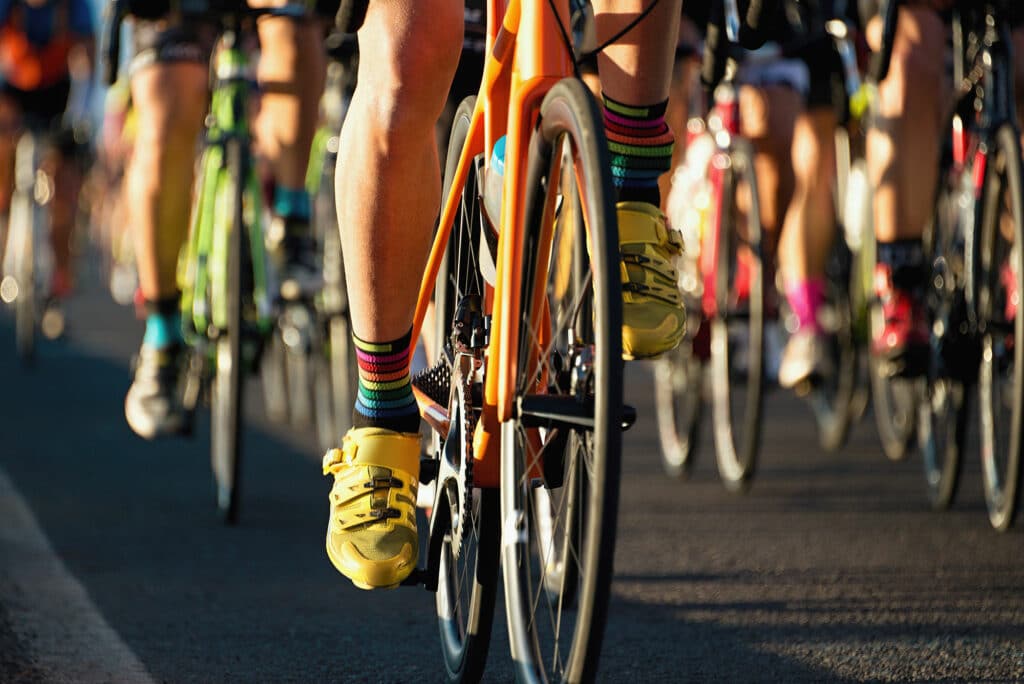 close up view of a crowd of cyclists biking on pavement.