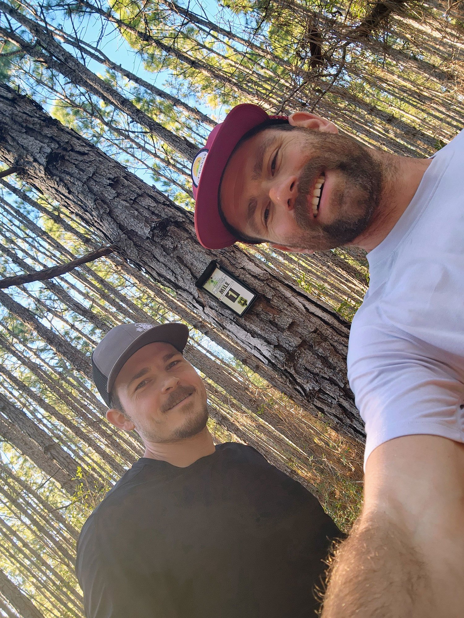 Photo of two men smiling and standing in the woods